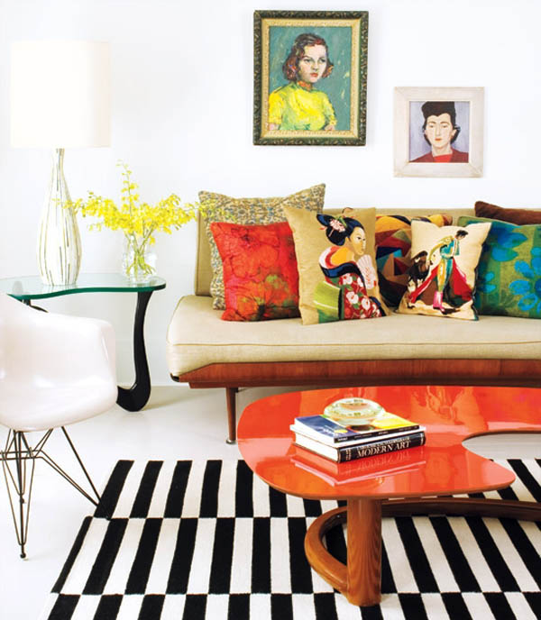 Living-Room-in-Apartment-with-Orange-Unique-Table-and-Bright-Cushions-above-Beige-Chair