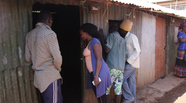 Area residents gather outside the room where the young boy spent the night before he was lynched together with the thugs/MIKE KARIUKI
