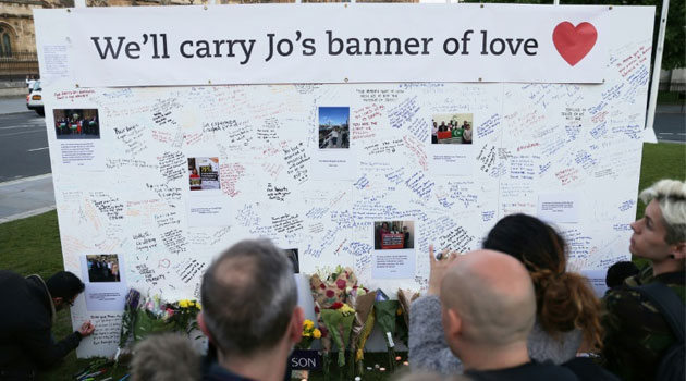 People stand in front of a large board in Parliament Square, central London, bearing messages in remembrance of murdered Labour MP Jo Cox/AFP