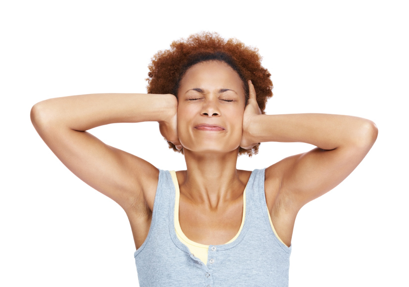Portrait of a unhappy young woman covering her ears over white background