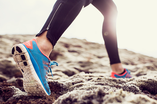 Close up of trainers running through mossy terrain