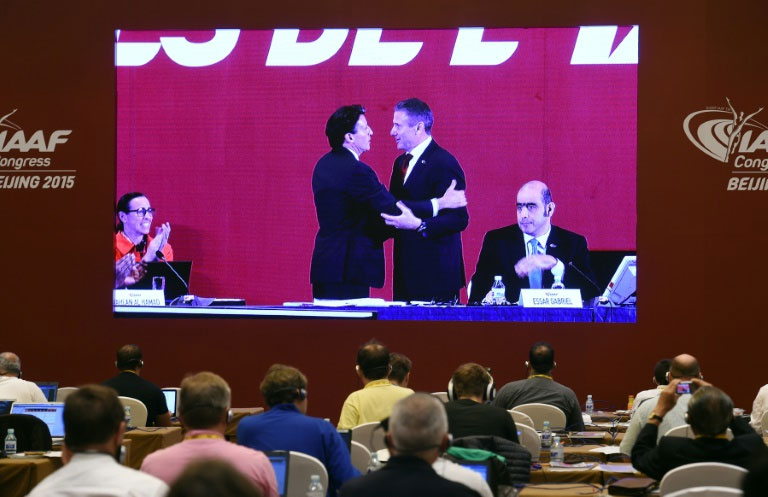 Journalists watch a screen in the media center showing a live feed of newly elected IAAF President Sebastian Coe (L) being congratulated by Sergey Bubka after the election results were announced at the IAAF Congress in Beijing on August 19, 2015. PHOTO/AFP