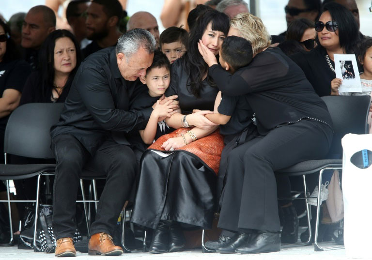 Widow of late New Zealand All Blacks rugby legend Jonah Lomu, Nadene Lomu (C) is comforted by her two sons, Brayley (C-L) and Dhyreille (C-R), her mother Lois Kuiek and father Mervyn Kuiek during memorial service on November 30, 2015. PHOTO/AFP